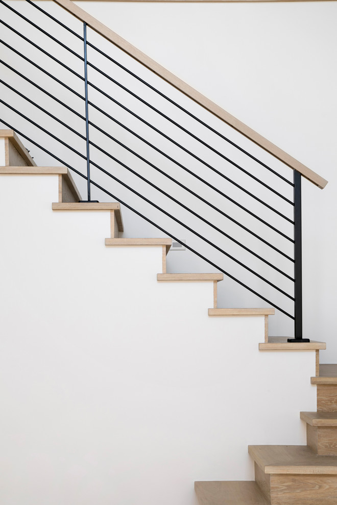 Immagine di una scala a rampa dritta minimalista di medie dimensioni con pedata in legno, alzata in legno e parapetto in metallo