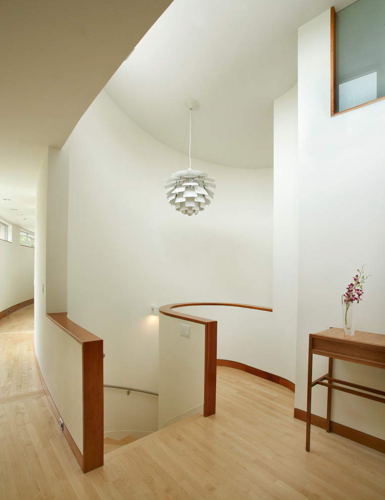 Diseño de escalera curva moderna de tamaño medio con escalones de madera y barandilla de metal