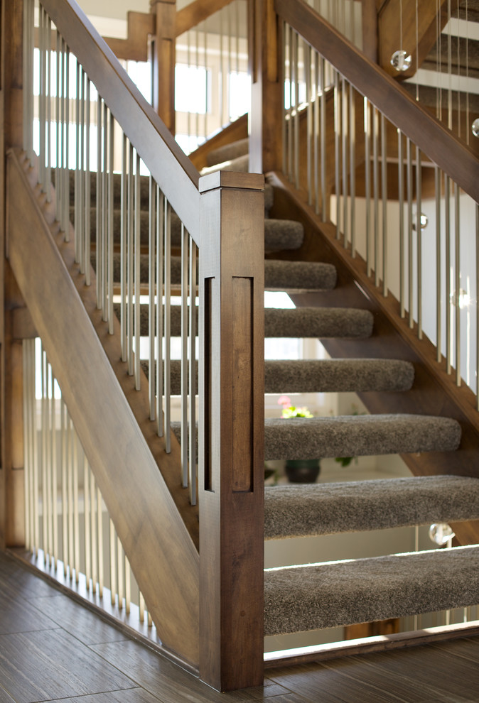 На фото: угловая лестница в современном стиле с ступенями с ковровым покрытием и деревянными перилами без подступенок с