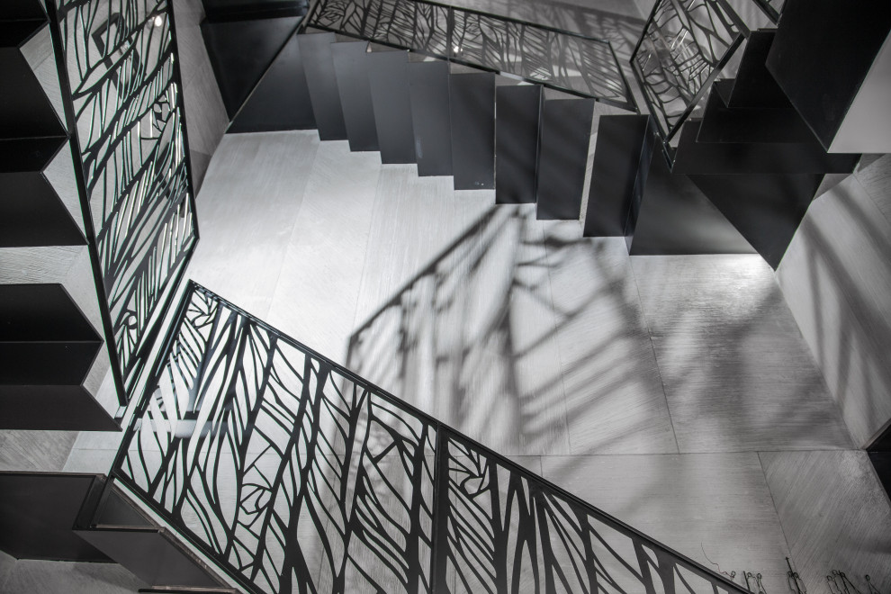 テルアビブにある高級な広いインダストリアルスタイルのおしゃれな折り返し階段 (金属の蹴込み板、金属の手すり) の写真