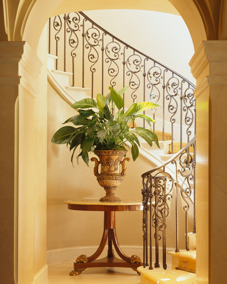Пример оригинального дизайна: изогнутая лестница среднего размера в классическом стиле с ступенями из известняка, подступенками из известняка и металлическими перилами