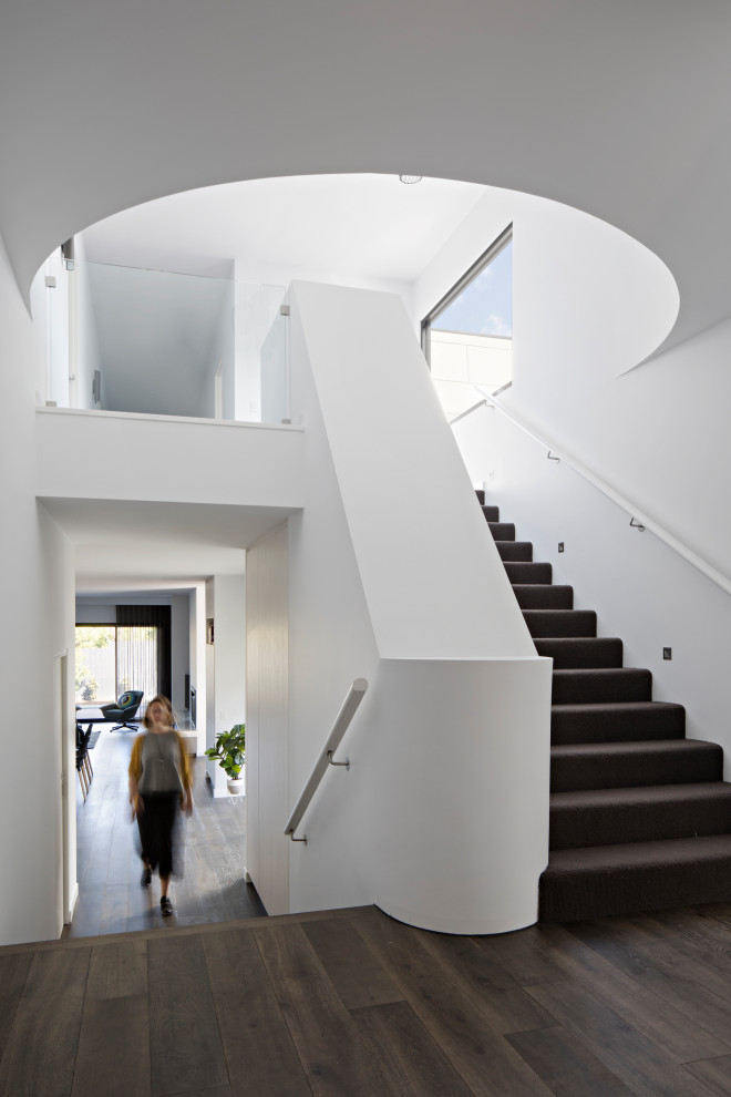 Пример оригинального дизайна: большая п-образная лестница в современном стиле с ступенями с ковровым покрытием, ковровыми подступенками и деревянными перилами