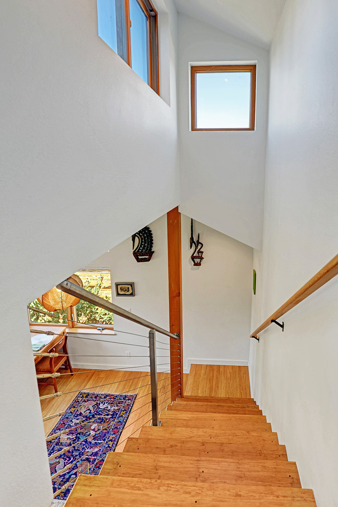 На фото: маленькая прямая металлическая лестница в стиле неоклассика (современная классика) с деревянными ступенями и перилами из тросов для на участке и в саду с