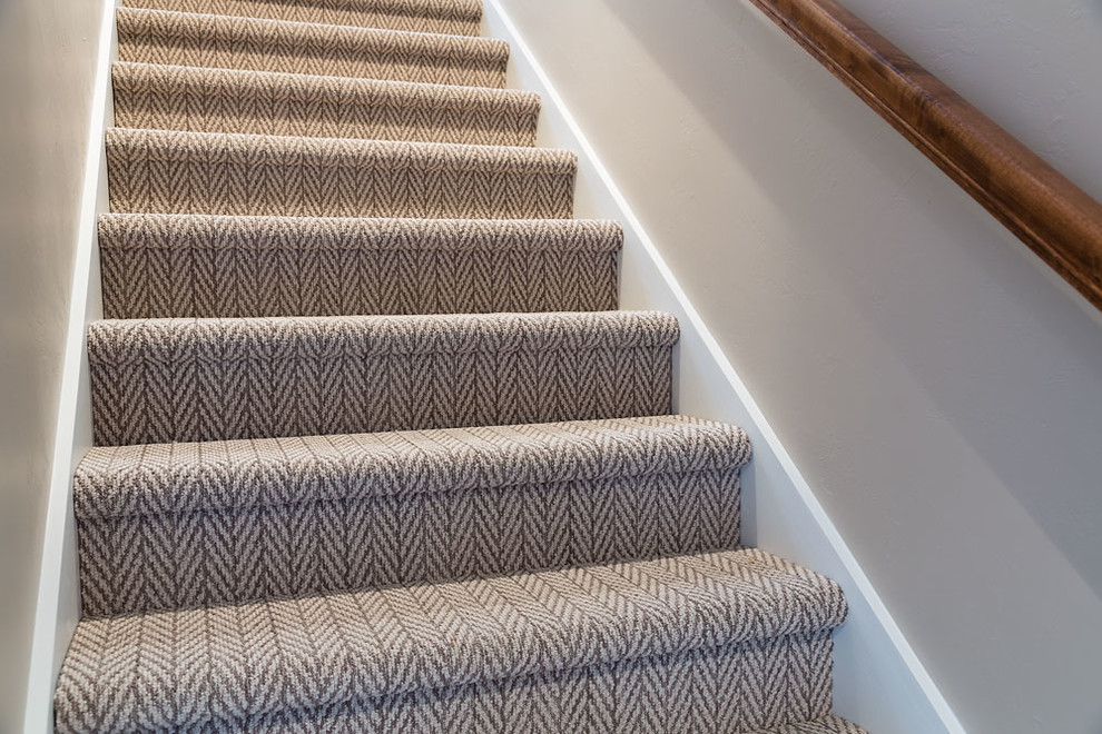 На фото: прямая лестница в стиле неоклассика (современная классика) с ступенями с ковровым покрытием, ковровыми подступенками и деревянными перилами с