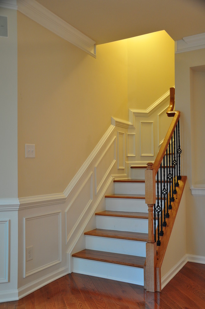 Ejemplo de escalera curva tradicional pequeña con escalones de madera, contrahuellas de madera pintada y barandilla de metal