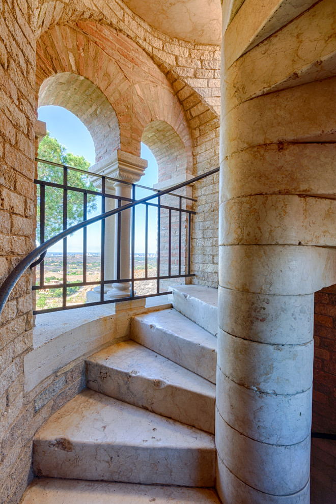 Foto de escalera en L rústica con escalones de mármol, contrahuellas de mármol y barandilla de varios materiales