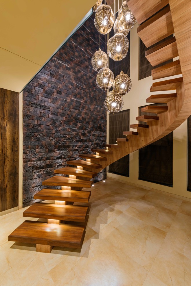 Cette photo montre un grand escalier sans contremarche courbe tendance avec des marches en bois et éclairage.