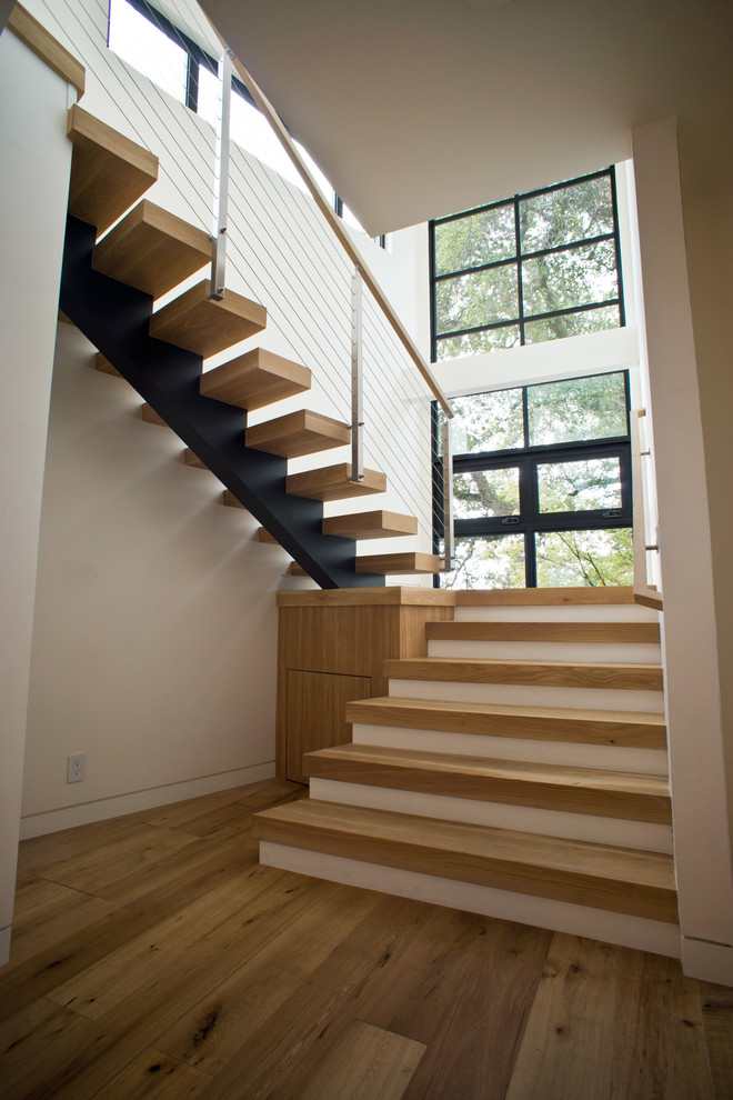 Immagine di una scala sospesa minimalista di medie dimensioni con pedata in legno e nessuna alzata