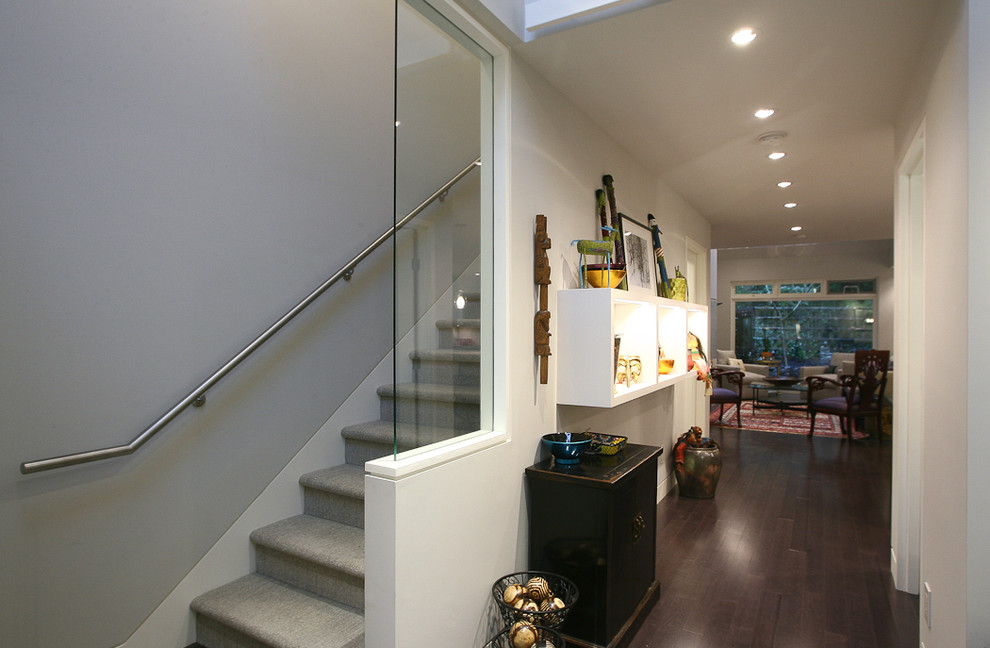 Cette image montre un grand escalier droit design avec des marches en moquette, des contremarches en moquette et un garde-corps en verre.