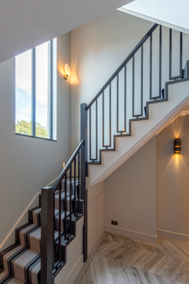 Mittelgroße Moderne Treppe in L-Form mit Teppich-Treppenstufen und Stahlgeländer in London