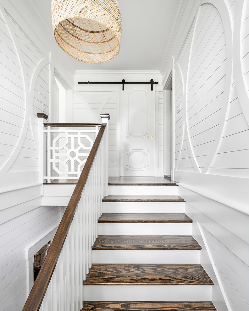 Large beach style wooden u-shaped wood railing and wall paneling staircase photo in Boston with painted risers