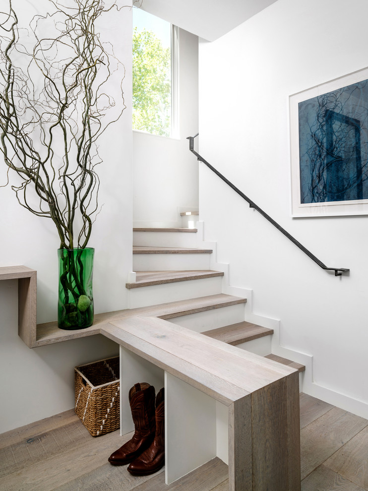 Cette photo montre un escalier peint nature en L avec des marches en bois, un garde-corps en métal et rangements.