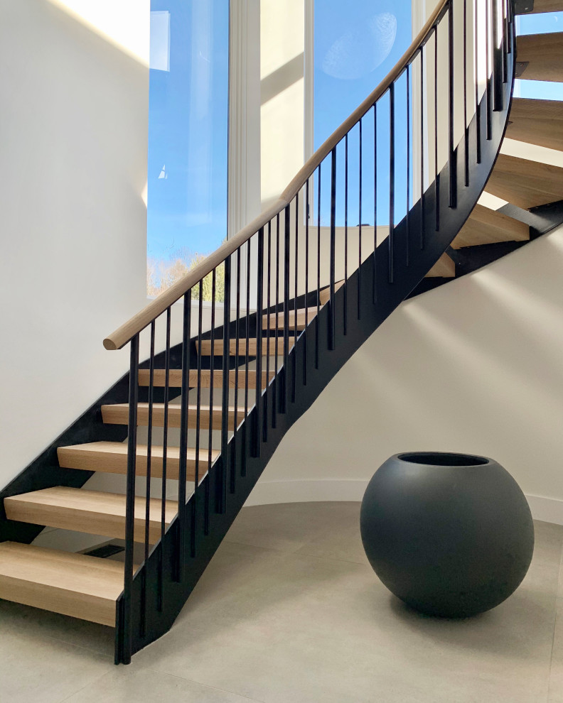 Стильный дизайн: большая изогнутая лестница в современном стиле с деревянными ступенями и металлическими перилами без подступенок - последний тренд