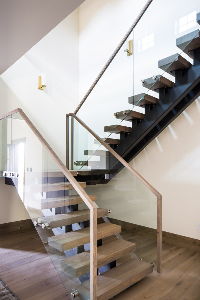 Idée de décoration pour un escalier chalet en L avec des marches en bois, des contremarches en verre et un garde-corps en bois.