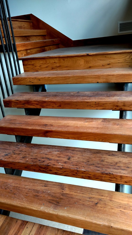 Modelo de escalera en L rústica sin contrahuella con escalones de madera y barandilla de metal