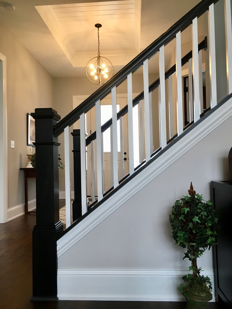 На фото: большая прямая лестница в стиле неоклассика (современная классика) с ступенями с ковровым покрытием, ковровыми подступенками и деревянными перилами с
