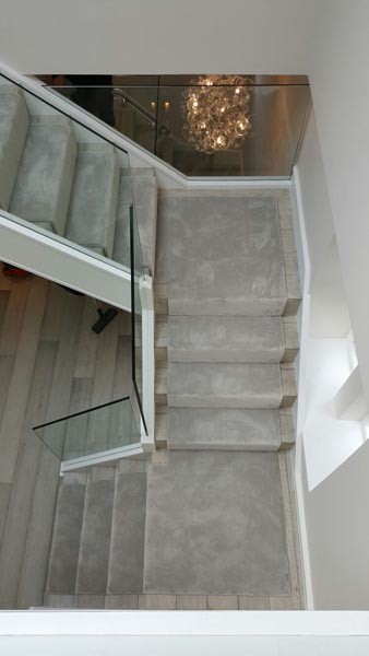 Imagen de escalera en U actual con escalones enmoquetados y barandilla de vidrio