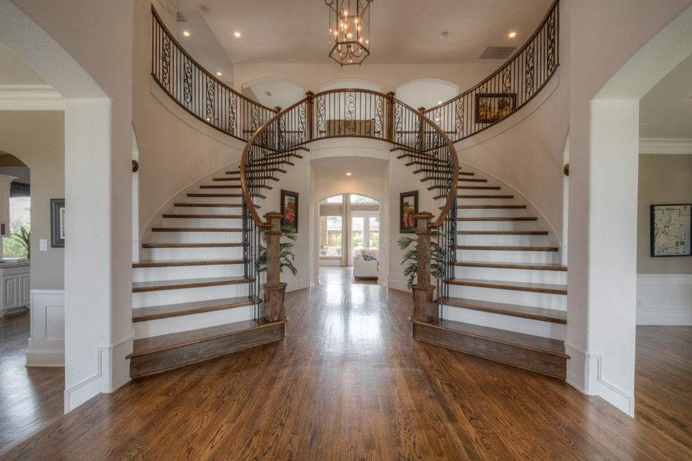 Свежая идея для дизайна: изогнутая лестница в классическом стиле с деревянными ступенями и крашенными деревянными подступенками - отличное фото интерьера