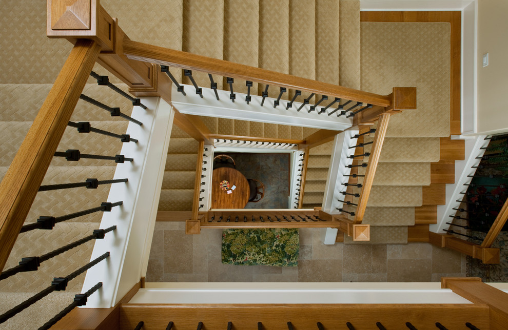 На фото: огромная винтовая лестница в классическом стиле с ступенями с ковровым покрытием, ковровыми подступенками и перилами из смешанных материалов с
