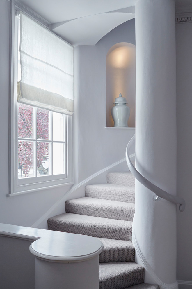 Идея дизайна: изогнутая лестница в стиле неоклассика (современная классика) с ступенями с ковровым покрытием, ковровыми подступенками и деревянными перилами