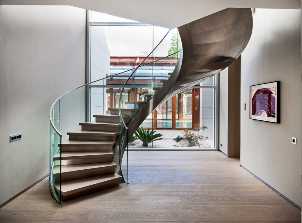 Réalisation d'un escalier courbe design avec des marches en bois et des contremarches en métal.