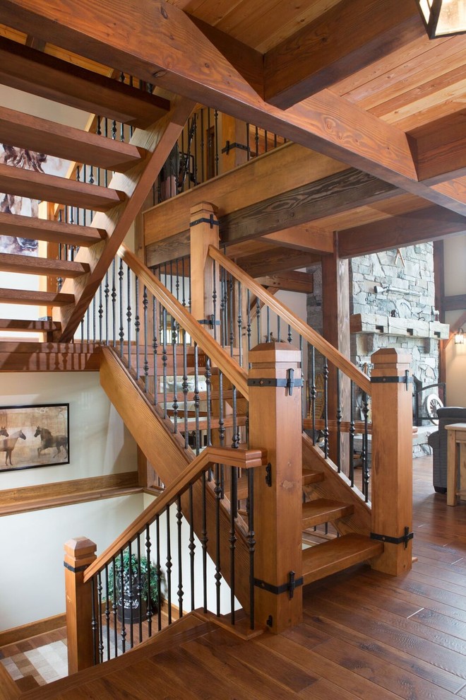На фото: большая изогнутая деревянная лестница в стиле кантри с деревянными ступенями