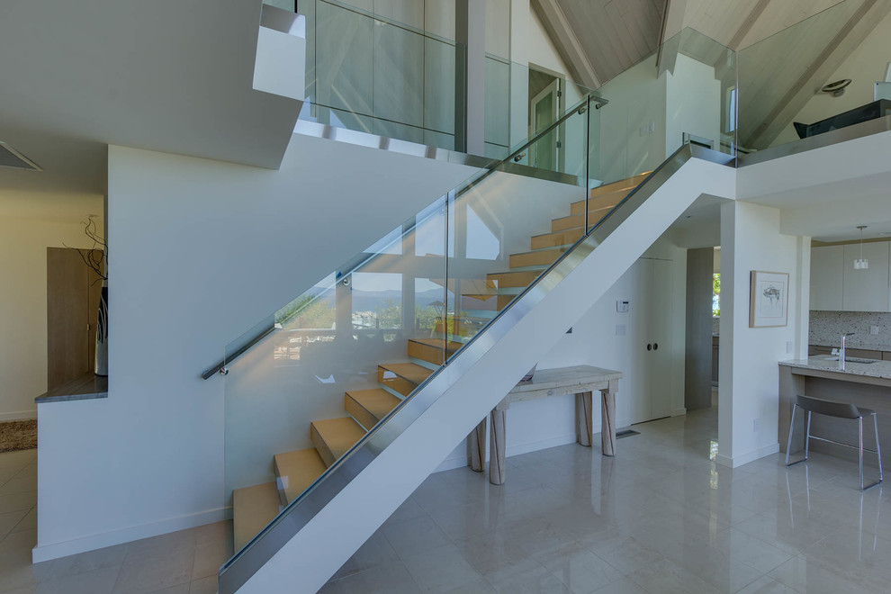 Свежая идея для дизайна: прямая лестница среднего размера в современном стиле с стеклянными перилами и ступенями из известняка без подступенок - отличное фото интерьера