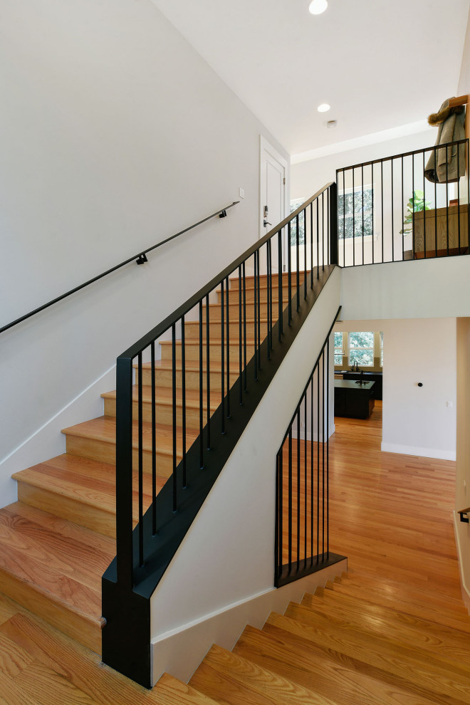Imagen de escalera en U minimalista con escalones de madera, contrahuellas de madera y barandilla de metal