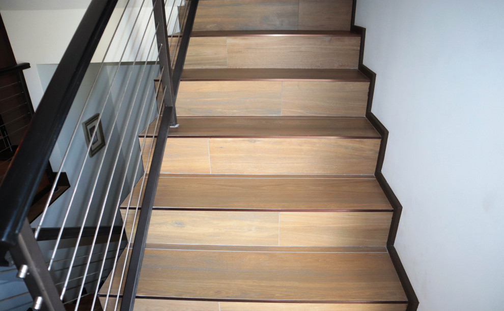 Cette photo montre un escalier carrelé tendance en U de taille moyenne avec des contremarches carrelées et un garde-corps en métal.
