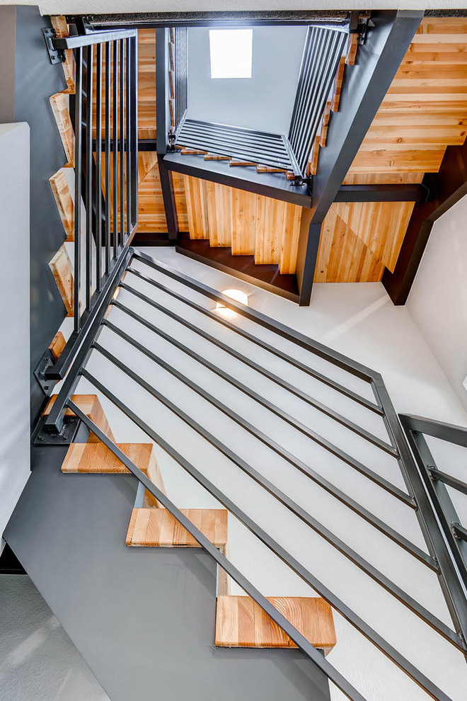 Cette photo montre un grand escalier sans contremarche hélicoïdal tendance avec des marches en bois et un garde-corps en métal.