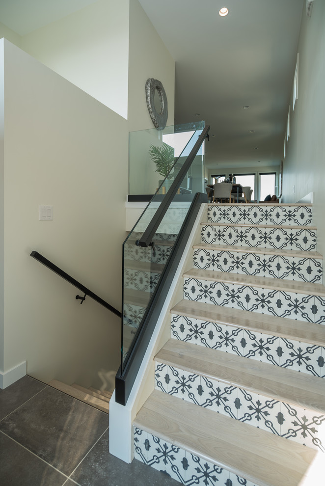 Свежая идея для дизайна: большая п-образная лестница в стиле модернизм с деревянными ступенями, подступенками из плитки и стеклянными перилами - отличное фото интерьера