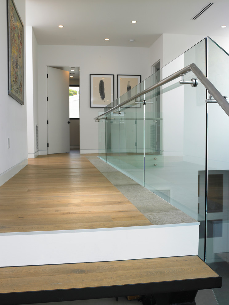Immagine di una scala minimal con pedata in legno e parapetto in vetro