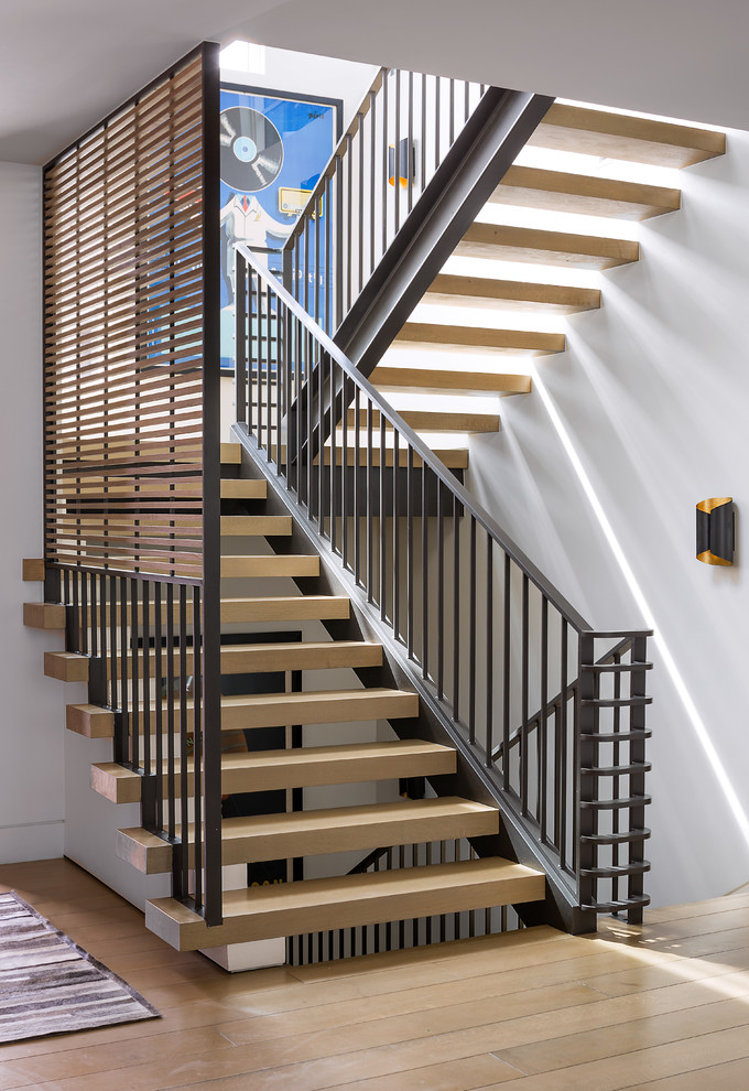 На фото: большая лестница на больцах в современном стиле с деревянными ступенями и металлическими перилами без подступенок с