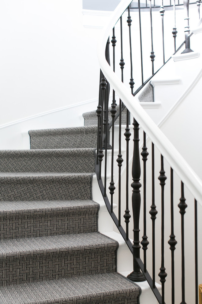 Cette photo montre un grand escalier courbe chic avec des marches en moquette, des contremarches en moquette et un garde-corps en matériaux mixtes.