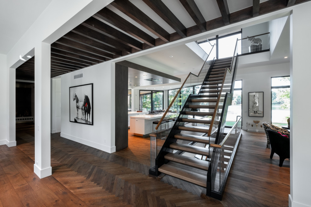 Ejemplo de escalera recta moderna grande sin contrahuella con escalones de madera y barandilla de vidrio