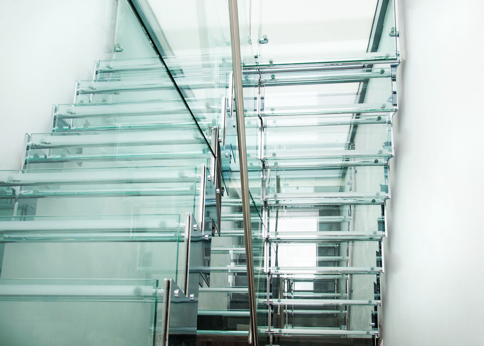 Foto de escalera recta actual de tamaño medio con escalones de vidrio, contrahuellas de metal y barandilla de varios materiales