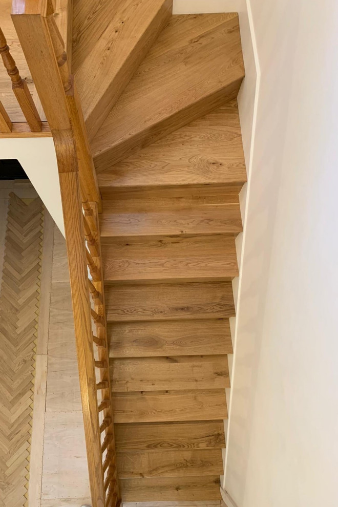 ハートフォードシャーにある広いトラディショナルスタイルのおしゃれならせん階段 (木の蹴込み板、木材の手すり) の写真
