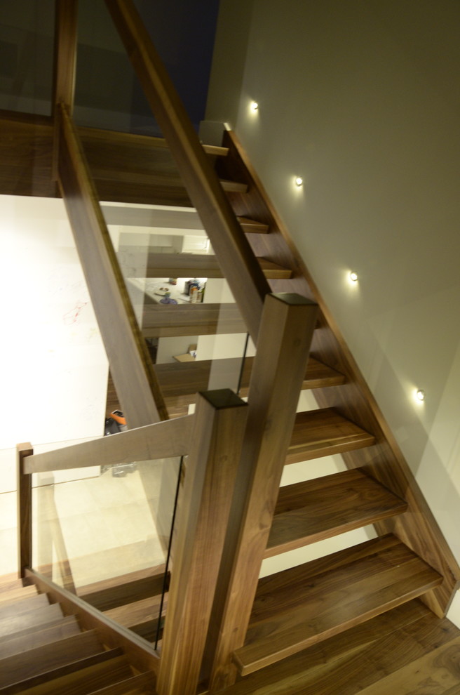 Photo of a medium sized modern wood l-shaped glass railing staircase in Other with open risers.