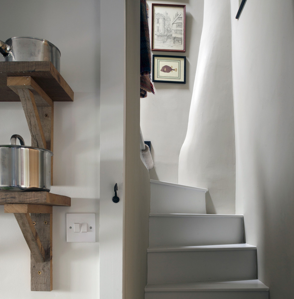 На фото: маленькая изогнутая лестница в стиле кантри с крашенными деревянными ступенями и крашенными деревянными подступенками для на участке и в саду с