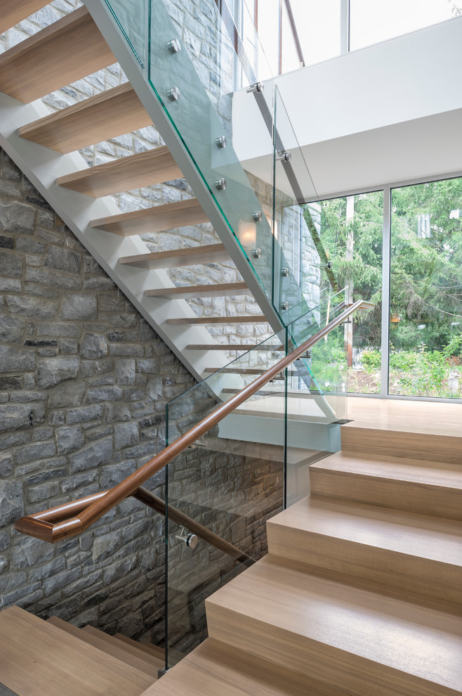 Aménagement d'un grand escalier contemporain en U avec des marches en bois, des contremarches en bois et un garde-corps en verre.