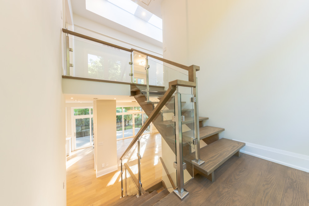 Foto de escalera suspendida contemporánea grande con escalones de madera, contrahuellas de madera y barandilla de vidrio