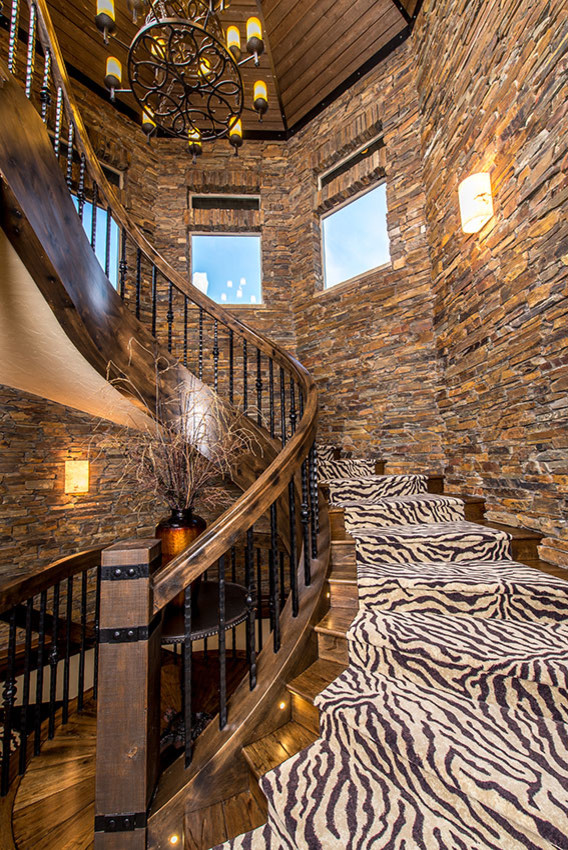 На фото: большая изогнутая деревянная лестница в стиле рустика с ступенями с ковровым покрытием с