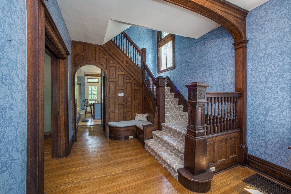 На фото: п-образная лестница в викторианском стиле с ступенями с ковровым покрытием, ковровыми подступенками и деревянными перилами с