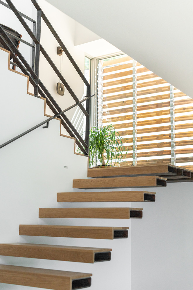 Inspiration pour un escalier sans contremarche flottant design avec des marches en bois, un garde-corps en métal et palier.