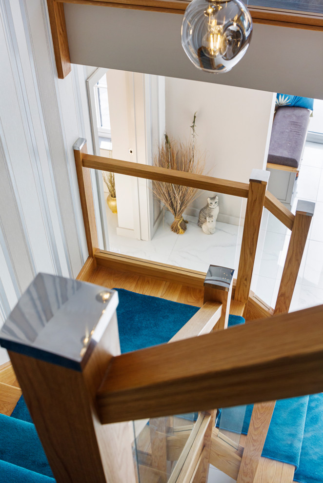 Diseño de escalera en U moderna extra grande con escalones de madera, contrahuellas enmoquetadas y barandilla de vidrio