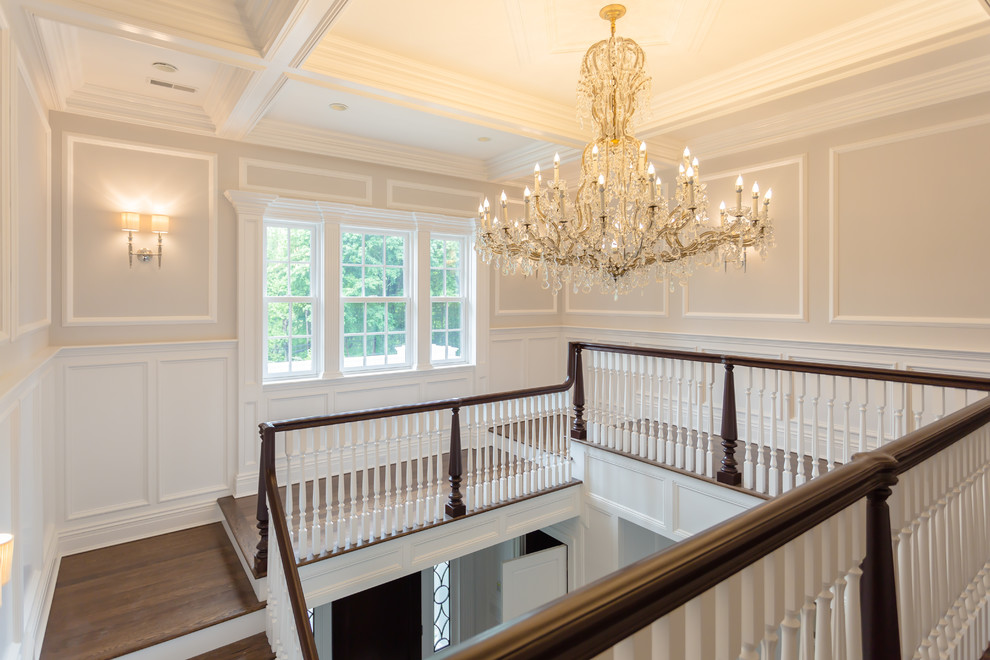 This is an example of an expansive traditional wood u-shaped staircase in New York with painted wood risers.