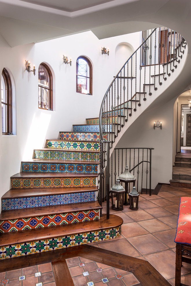 Diseño de escalera curva mediterránea con contrahuellas con baldosas y/o azulejos, escalones de madera y barandilla de metal