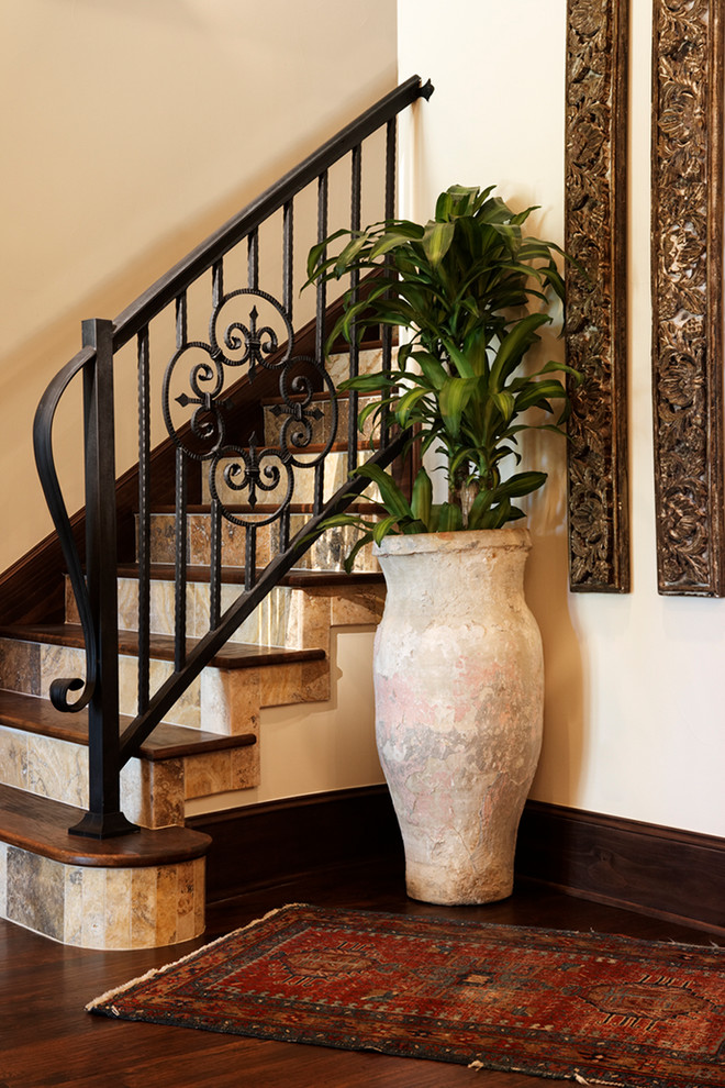 Example of a large tuscan wooden curved metal railing staircase design in Austin with tile risers