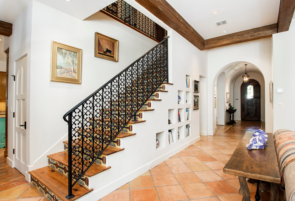 Ejemplo de escalera recta mediterránea con escalones de madera, contrahuellas con baldosas y/o azulejos y barandilla de metal