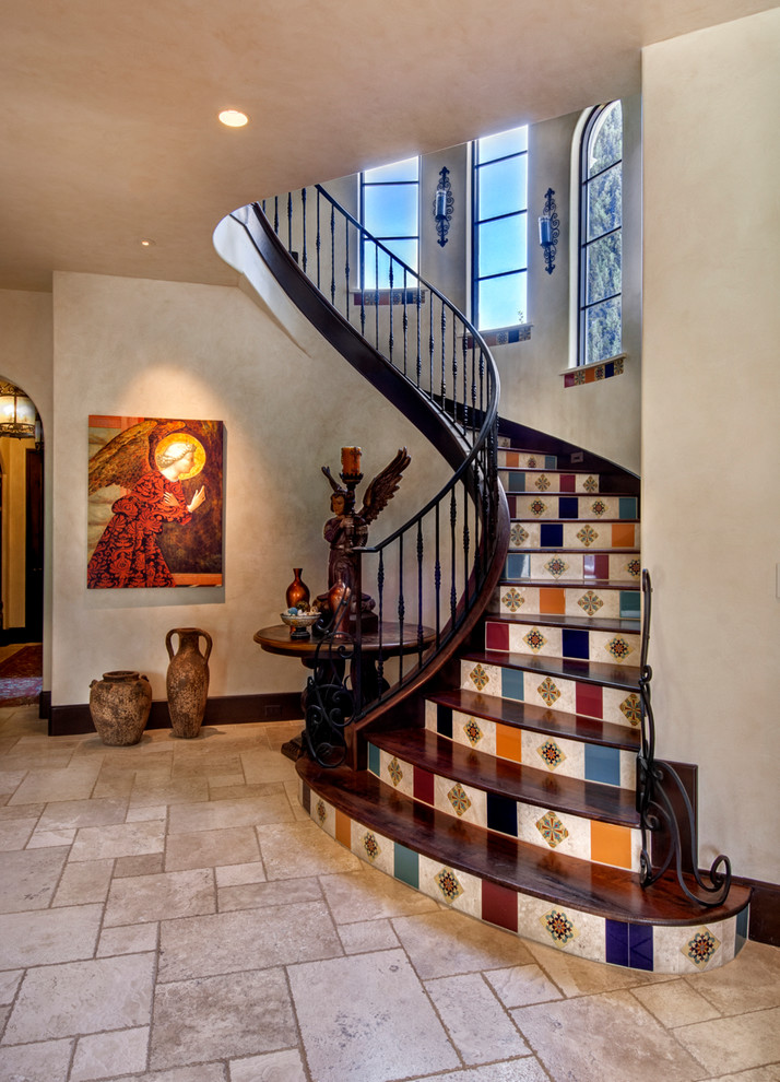 Источник вдохновения для домашнего уюта: изогнутая лестница в средиземноморском стиле с деревянными ступенями, подступенками из плитки и металлическими перилами